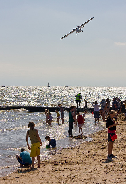 A Catalina displays above the children paddling in the waves