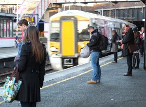 Passengers wait for the 07:44 as the 07:40 fast to Brighton runs through Kentish Town